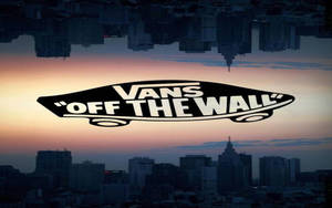 Vans Off The Wall 標誌漂浮在日落時分的城市上空，帶有水倒影。