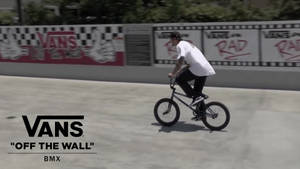 BMX車手在混凝土坡道上表演技巧，身後有Vans塗鴉牆。