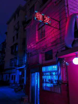 霓虹粉紅和藍色燈光在夜晚的城市小巷中閃耀，附近停著一輛摩托車。 — Kindle 壁紙
