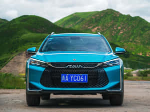 藍綠色SUV停在泥路上，背景有綠色山丘。 — 酷車 壁紙