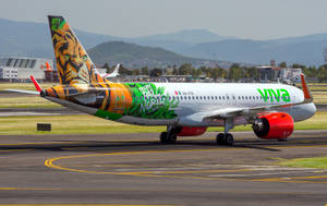 Viva Aerobus老虎塗裝飛機在機場停機坪上，靠近山脈 — 妖精尾巴 壁紙