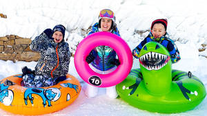 三個穿著雪地裝備的孩子在雪地裡的充氣管上大笑。