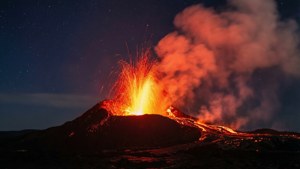 火山在夜間爆發，明亮的熔岩和煙霧在星空下