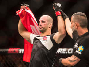 UFC拳手手持加拿大國旗慶祝勝利，裁判舉起他的手臂。