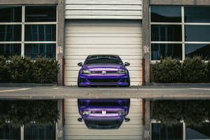 紫色 Volkswagen GTI 停在車庫前，帶有水坑倒影