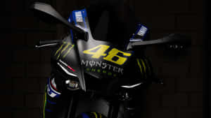 特寫一架黑色Yamaha賽車電單車，帶有黃色46 Monster Energy貼紙，背景為磚牆。 — 機車 壁紙