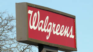Walgreens商店招牌，紅色背景白色字體，背景為藍天和光禿的樹枝。