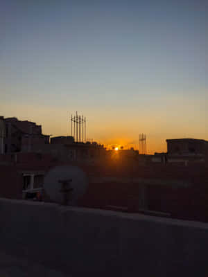 夕陽下的都市屋頂，帶有衛星天線和建築剪影