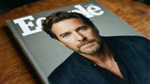 一個木質表面上帶有男性肖像的雜誌封面。