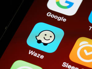 智能手機屏幕顯示Waze應用程式圖標，帶有微笑鬼魂吉祥物。