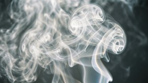 白色煙霧在深灰色背景上以柔和發光的圖案旋轉