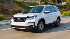 白色本田 Pilot SUV 在日落時分行駛在風景優美的高速公路上。 — 本田 壁紙
