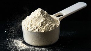 黑色表面上量勺中的白色粉末及灰塵微粒。