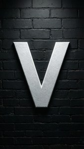 一個銀色字母V安裝在黑色磚牆上，帶有聚光燈。