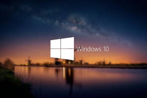 Windows 10 標誌在暮色景觀上，有風車和水面倒影。
