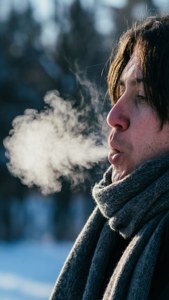 在雪地冬季風景中呼出蒸氣的人，戴著灰色圍巾