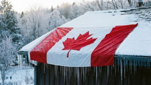 加拿大國旗在積雪屋頂上，冰柱懸掛在冬季森林