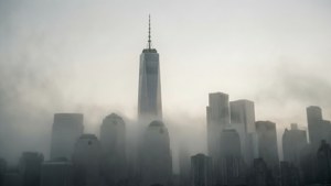 霧氣瀰漫的城市景觀，世界貿易中心一號大樓從雲層中浮現。