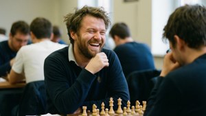 男子在棋盤對面與對手進行國際象棋比賽時大笑。