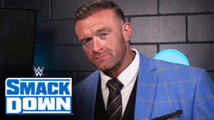WWE摔角手Finn Balor身穿藍色西裝，磚牆背景上有SmackDown標誌。 — 摔角 GIF 壁紙