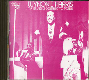 Wynonie Harris 在洋紅色調照片中與樂隊在舞台上表演藍調音樂。