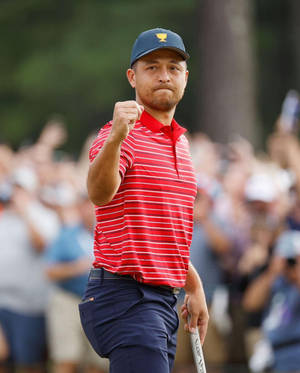 高爾夫球手在陽光明媚的球場上舉起握著球桿的拳頭慶祝勝利。
