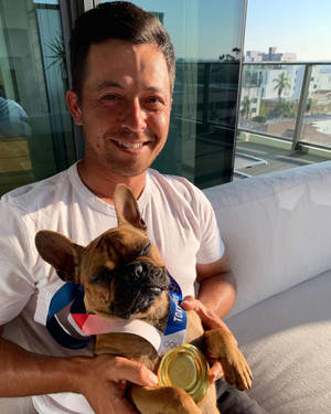 男人抱著一隻脖子上掛著奧運金牌的法國鬥牛犬。