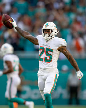邁阿密海豚隊25號球員在球場上拿著足球慶祝。 — NFL 美式足球 GIF 壁紙