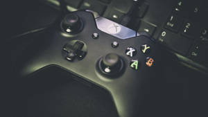 黑色Xbox手掣放在鍵盤上，按鈕在昏暗光線中發光。
