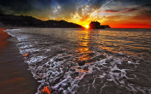 夕陽下的海洋，海浪在戲劇性的雲層下拍打沙灘