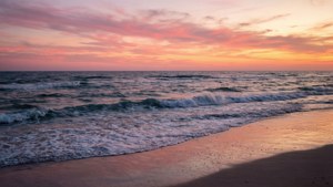 夕陽下的海洋，海浪沖刷著沙灘