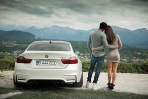 情侶喺白色BMW M4附近擁抱，俯瞰群山。