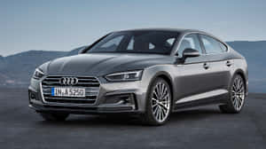 銀色Audi A5 Sportback停泊在戶外，以山巒為背景。 — 奧迪 GIF 壁紙