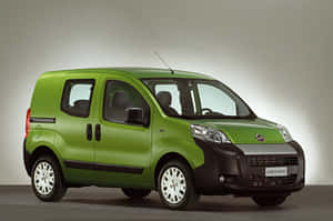 一輛青檸綠色的菲亞特 Fiorino 貨車，帶有黑色飾條和白色輪圈，在攝影棚環境中。 — MacBook Air M4 壁紙