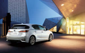白色Lexus CT 200h在黃昏時停在現代玻璃建築前。 — Steam Deck 壁紙