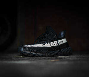 黑色Yeezy Boost 350運動鞋，在深色混凝土上帶有白色條紋