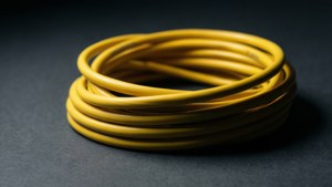 深灰色紋理表面上的盤繞黃色電線