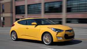 黃色現代Veloster在城巿街道上行駛，背景模糊。 — 現代汽車 壁紙