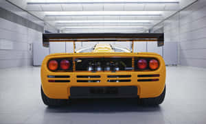 黃色McLaren F1超級跑車後視圖，位於乾淨的白色車庫中。 — 4K 法拉利 壁紙