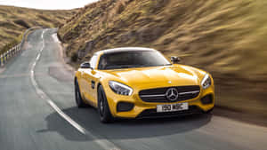 黃色 Mercedes 跑車在日落時分於蜿蜒的山路上疾馳。 — 平治 AMG 壁紙