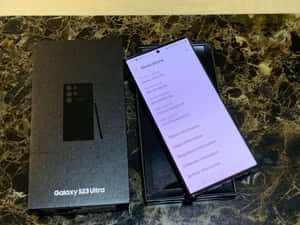 Samsung Galaxy S23 Ultra手機在大理石上於盒子旁邊顯示設定。 — Samsung S23 Ultra 壁紙