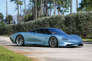 淺藍色McLaren Speedtail停泊在綠樹成蔭的道路上。 — MacBook Air M2 壁紙