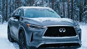 冬季時灰色 Infiniti SUV 停泊在雪地森林中。