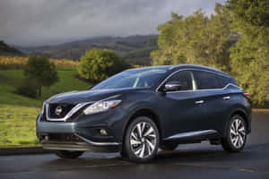 深藍色日產Murano SUV停泊在濕滑的道路上，附近有綠色山丘和樹木。 — Surface Pro 壁紙