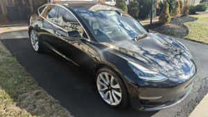 黑色Tesla Model 3停泊在陽光明媚的住宅車道上，帶有樹木倒影。 — Tesla GIF 壁紙