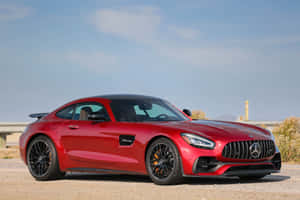 紅色Mercedes-AMG GT R跑車停在碎石上，背景有山丘。 — Surface Pro 壁紙