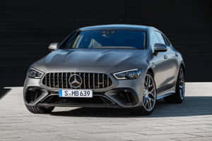 啞光灰色梅賽德斯-AMG GT 63 S 轎跑車停在路面上，背景是深色牆。 — 平治 AMG 壁紙