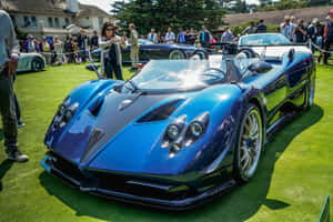 藍色帕加尼 Huayra 跑車在草地上，車展有觀眾。 — Surface Pro 壁紙