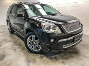 黑色GMC Acadia SUV停在室內混凝土地板上，背景為白色磚牆。 — 4:3 壁紙