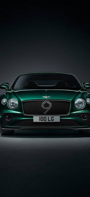 在攝影棚燈光下，深色背景中的綠色 Bentley 豪華車。